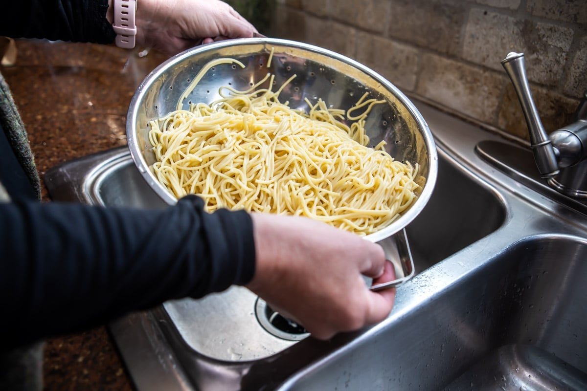 A colander full of cooked spaghetti.