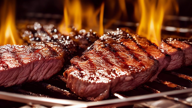 Steaks grilling over open flames